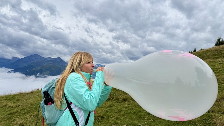 Evil-Lyn blow to pop a Cattex 18 inch Stuffer-Balloon in the Kitzbueheler Alpes